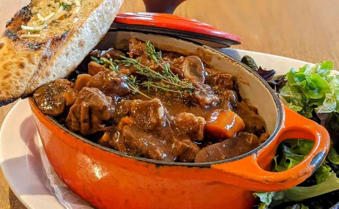 A braised dish in an orange cast-iron pot at Dottie Audrey’s
